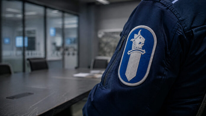 Poliisin miekkaleijonatunnus tilannehuoneessa Poliisin miekkaleijonatunnus tummansinisen virkapuvun hihassa modernissa tilannehuoneessa.